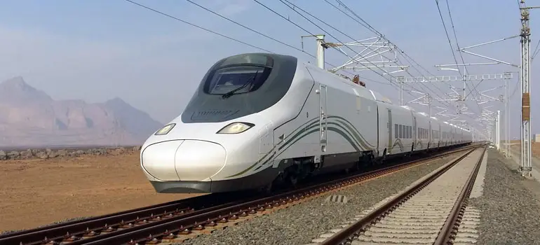 High-speed Haramain High Speed Railway train traveling along tracks through the Saudi desert between Jeddah and Madinah.