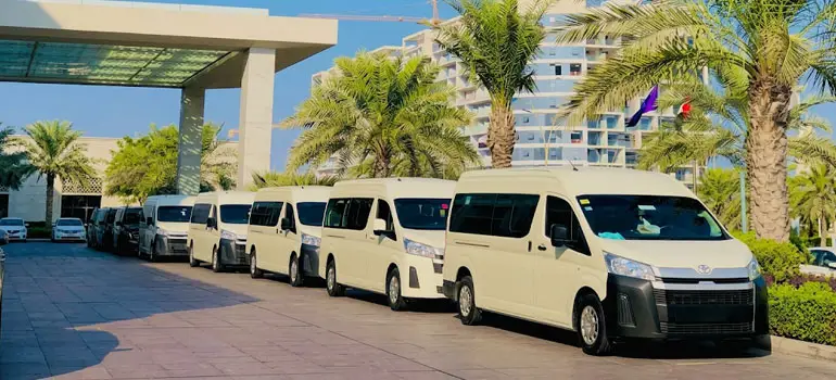 Row of white vans parked at a hotel entrance with palm trees in Saudi Arabia.