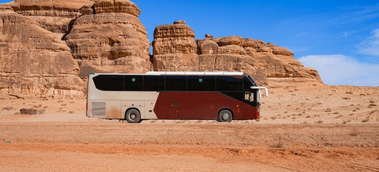 Luxury coach for group private transport amid the sandstone rock formations of Al Ula.