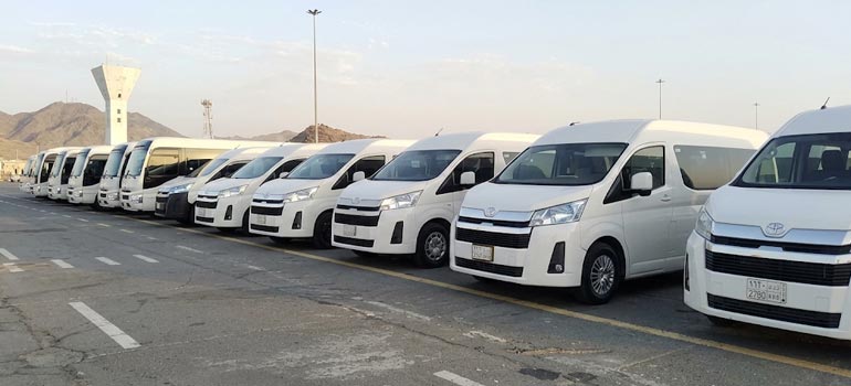 Fleet of white private vans ready for group transport and transfers in Madinah.
