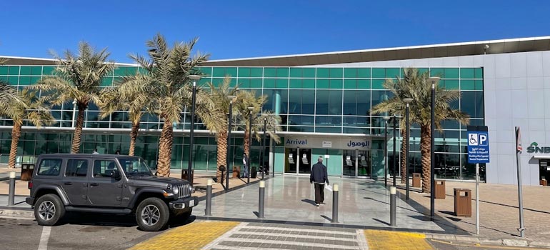 Private Jeep transfer vehicle parked at Tabuk Airport arrivals terminal for airport transport service.